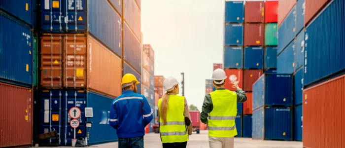 Operaciones de logística internacional en puerto con contenedores y equipo supervisando carga para importación y exportación